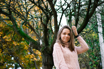 beautiful girl in a pink knitted sweater stands near a fairy tree