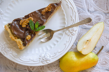 Chocolate pear tart, portioned slice on a white plate. Daylight, selective focus, horizontal photo