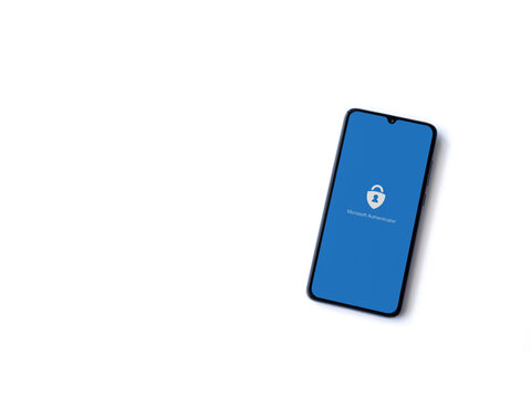 Lod, Israel - July 8, 2020: Microsoft Authenticator app launch screen with logo on the display of a black mobile smartphone isolated on white background. Top view flat lay with copy space.