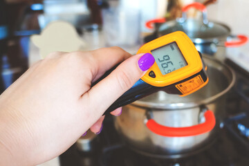 Kitchen measuring infrared thermometer. Pyrometer in a hand when cooking