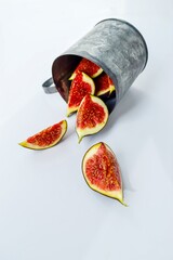 Bright red ripe figs in a metal mug on a white background.