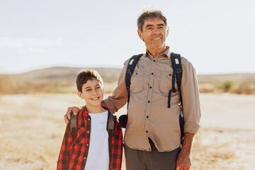 Latin grandfather and grandson with backpacks hiking in the mountains.