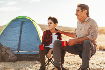 Grandfather and grandson having fun in camping. Concept of elderly people with active life.