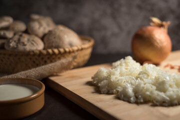 Fototapeta na wymiar Closeup of fresh white mushrooms in a basket with chopped onions on a cutting board