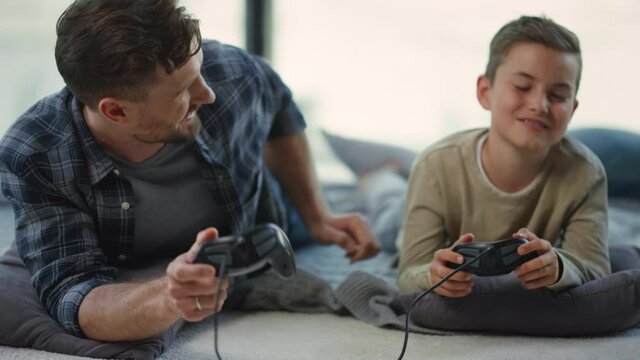 Father and son playing on console indoors. Parent and kid gaming on play station