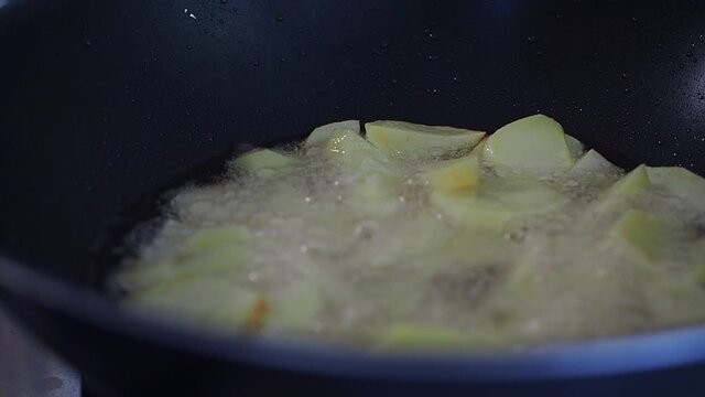 Preparing something to eat for lunchtime at home. Sliced potatoes are fried in a pan with boiling oil.