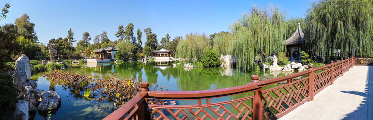 a stunning panoramic shot of the still green lake waters, weeping willows and other lush green...