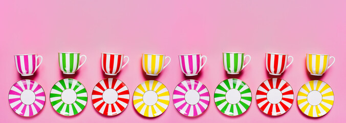 Set of color plates and mugs with  a stripes pattern  on pink background. Pattern. Banner