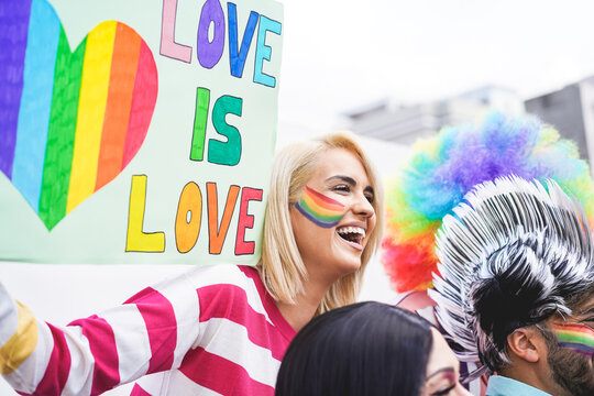Girl holding a banner at a gay pride parade - Lesbian woman having fun at fest event - Lgbt and love concept - Focus on woman face