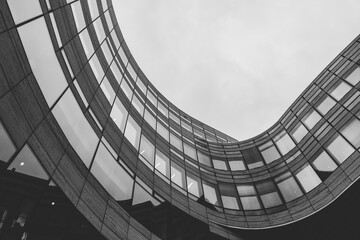Low angle greyscale shot of a modern building captured on a cloudy day