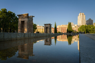 The Egyptian Temple of Debod and the surrounding buildings reflected in the waters of the pond on a spring afternoon, Madrid, Spain