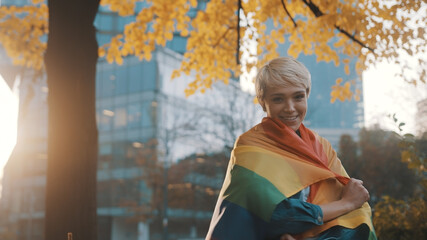 Beautigul young caucasian blond short haired woman covering herself with rainbow flag. High quality photo - obrazy, fototapety, plakaty
