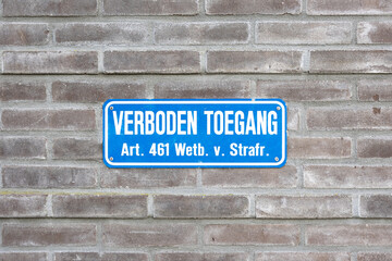 Fototapeta na wymiar Sign attached to a wall with the Dutch text 'prohibited access for unauthorized persons, article 461 penal code'. Official Dutch 'No Entry' sign.
