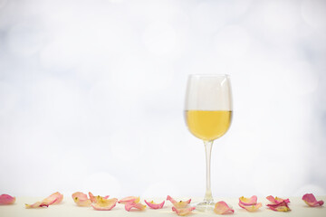 Isolated glass of white wine on white background with rose petals