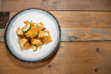 A delicious plate of fried chicken with chilli mayonnaise mayo and cucumber slices on a wooden...