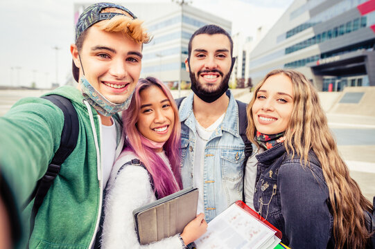 Selfie time! Four international students with beaming smiles are posing for selfie shot outside school -  Gathered, cheerful, smart and successful youth - Lifestyle concept