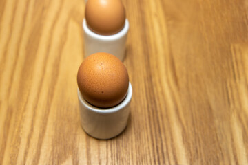 Delicious hard boiled eggs in little egg cups in a row on a wooden background