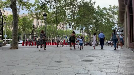 Time lapse footage of people walking on famous luxury shopping street called "Passeig de Gracia" in Barcelona. It is a summer day.