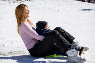 Mother and son sliding on mountain slope
