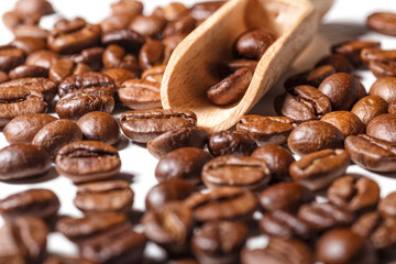 Freshly roasted coffee beans background.Dark roasted coffee beans with scoop on wooden background.