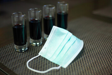 Slightly blurred Face mask with an alcoholic drink in a bar
