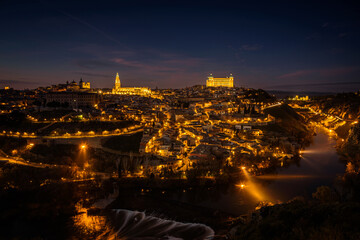 Beautiful view of Toledo city skyline with Cathedral, Alcazar and Tagus river at night, Spain