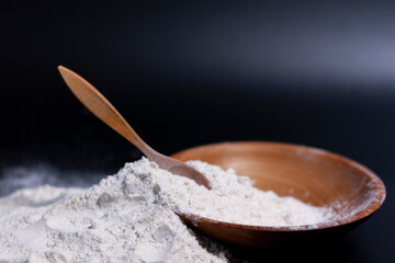 At the bottom of the screen is a bunch of wheat spikelets, a Cup and a wooden spoon. Slide of white flour. Closeup. 