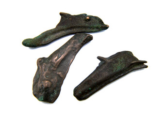 antique copper coin in the shape of a dolphin on a white background
