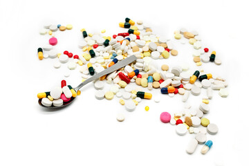 Spoon full of colourful pills and medicines isolated in white background