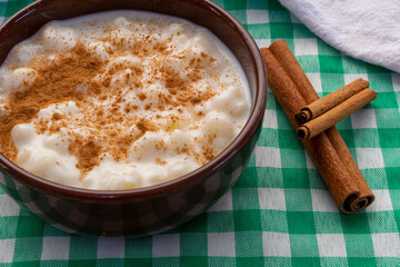 White corn cooked with milk known as hominy, hominy or mungunza, with cinnamon, in a bowl on a green towel.