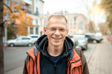 Portrait of smiling mature man in casual autumn clothes on city street