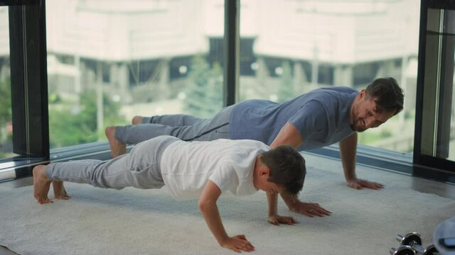 Father and son exercising together. Man and boy making push ups at home.