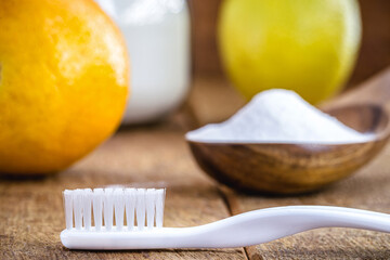 toothbrush with glass with baking soda and citrus fruits like lemon or orange in the background....