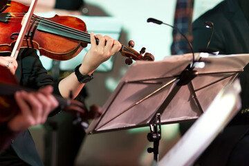 Symphony music. Woman playing the violin in orchestra near music note stand