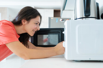 Fototapeta na wymiar The girl warms food in the microwave. A quick snack
