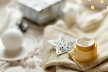 Details of still life in the home interior living room. Orange Opened plastic container, jar.of cream over Christmas lights bokeh in home. holiday decoration, magic Christmas. Selected focus