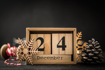 Closeup of the wooden calendar of blocks with the date of December 24 on the black background. Merry Christmas mood.