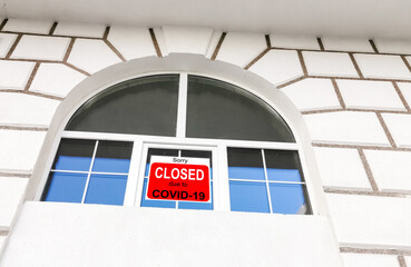 Business center closed due to COVID-19, sign with sorry in door window. Stores, restaurants,...