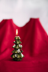 Christmas tree figurine candle burn on red white backdrop. Cover for postcards.