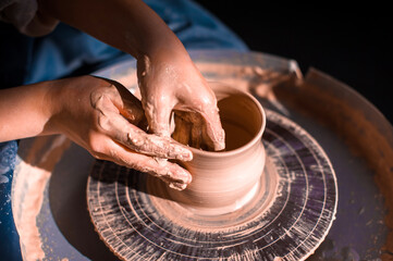 Close-up of potter's hands with the product on a potter's wheel