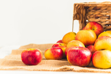 Fresh yellow and red apples in the wicker basket on the white background. Autumn harvesting