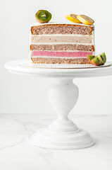 Fruit cake cut on the white background.  Sponge biscuit and fruit mousse layered cake. Tropical fruit cake