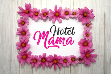 Hotel Mama. Hintergrund mit Rahmen aus rosa Blumen, Handschrift, weißes Holz. 