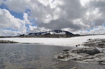 Snowy mountain peaks with an ice lake and rocks on a hike in Norway