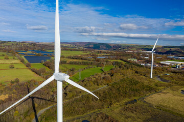 Aerial View of 2 large wind turbine stationary on beautiful welsh landscape. clean energy concept. close up shot