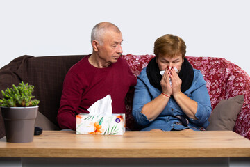 The husband is caring for a sick wife who has a runny nose and sore throat. An elderly couple is struggling at home with a viral infection and sore throat.
