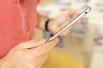 Caucasian man smiles and uses a tablet in the living room. Close up shot. Daylight
