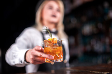 Focused woman barkeeper places the finishing touches on a drink  