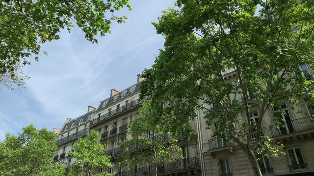 Footage of historical, traditional buildings and trees showing French / Parisian architectural style in Saint-Germain area of Paris. It is a sunny summer day. Camera moves forward.