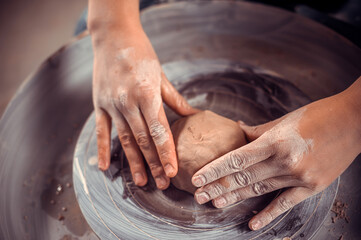 The potter works in the workshop. Hands and a potter's wheel close-up